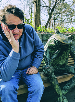 Dow Man with dark hair sitting next to a frog sculpture