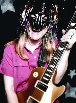 Mary Woman wearing a party mask holding a guitar with stars on the wall behind her
