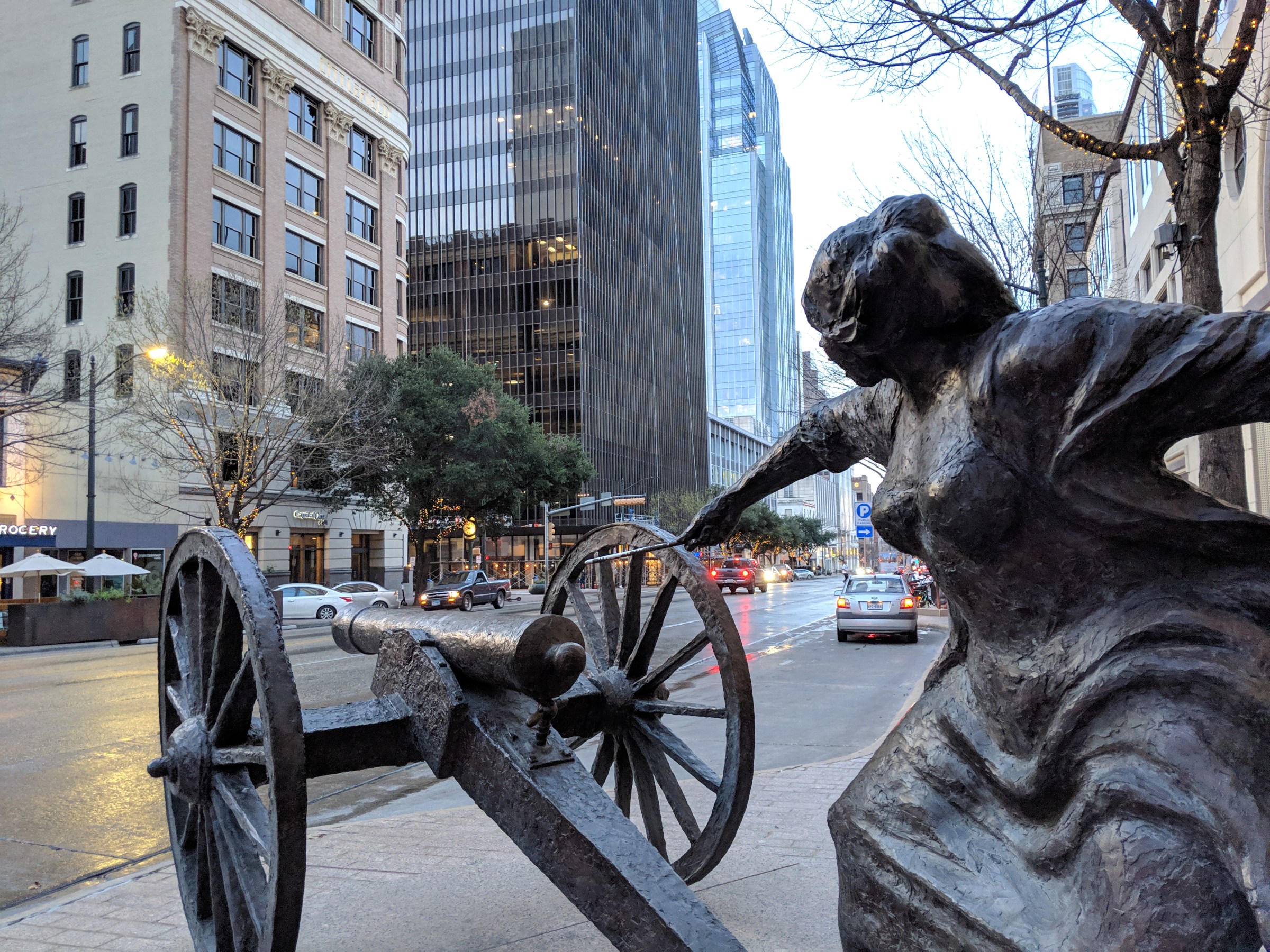 a statue of a woman lighting a cannon on a city street