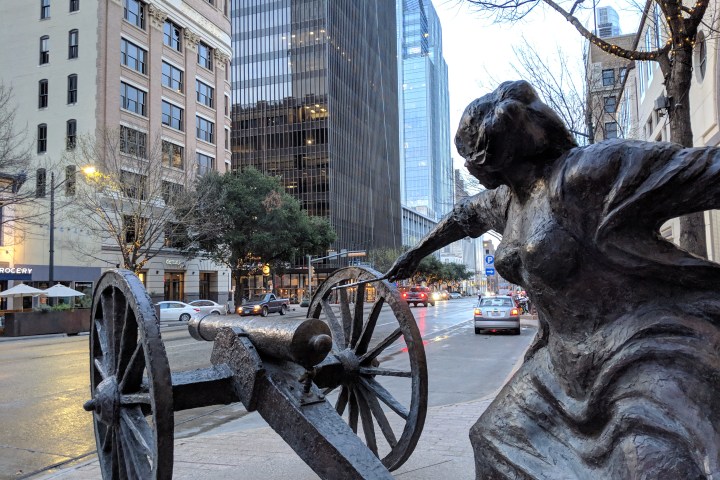 a statue of a woman lighting a cannon on a city street