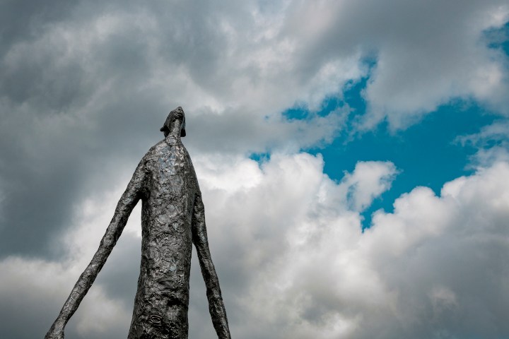Metail sculputer that resembles tin fold of a long armed being looking up into the sky.