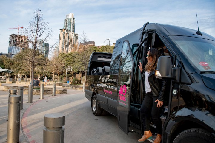 Woman exiting the black AO Tours Austin Panoramic Bus with Downtown Austin in the background.