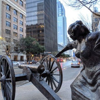 a statue of a woman lighting a cannon on a city street