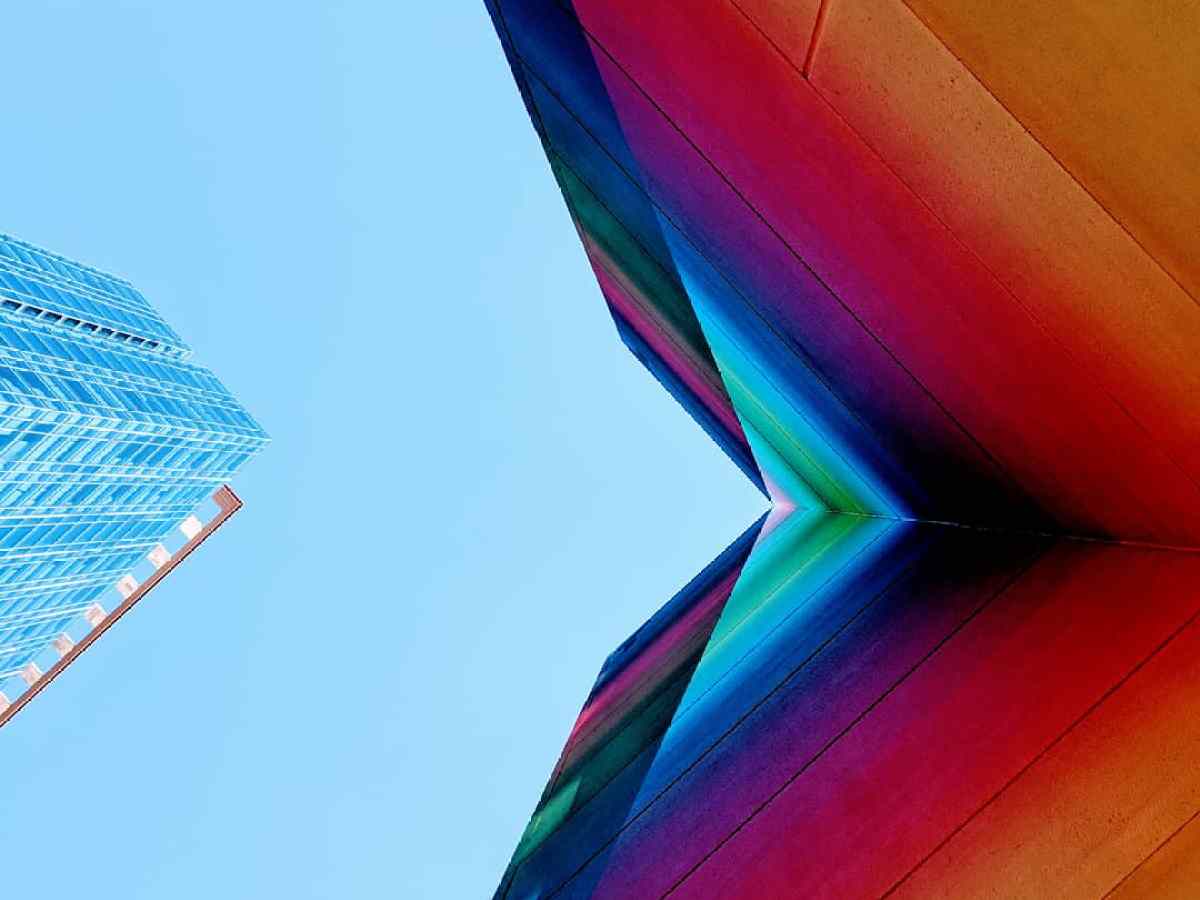 Lookin up to the sky with a colorful mural on a wall with building and clear blue sky