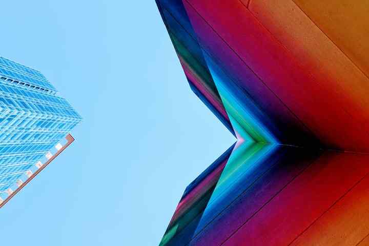 Lookin up to the sky with a colorful mural on a wall with building and clear blue sky