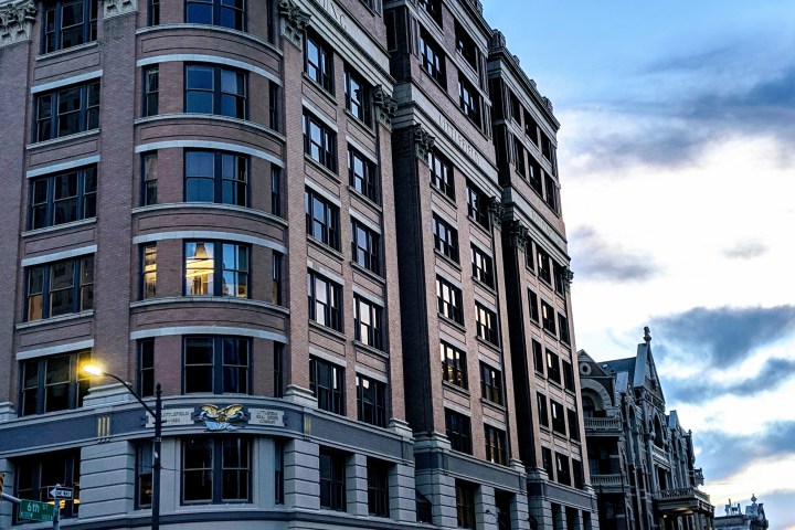 Older style building early in the morning. Street is wet. Sky is blue with some clouds