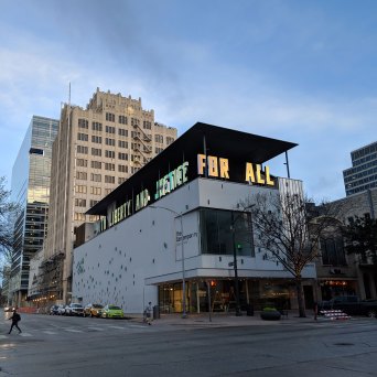 View of a building with white walls and blue blocks. With the words 