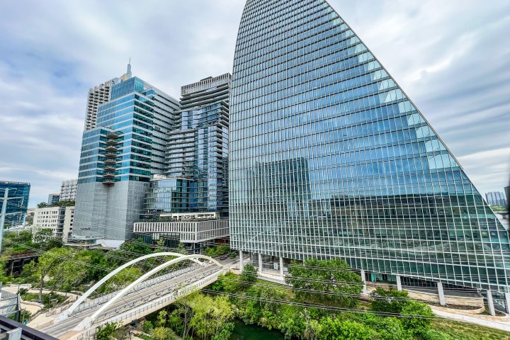 View of the butterfly bridge in Austin, TX from the Austin Central Library's roof top garden. Tall glass buildings, trees, overcast cloudy sky.