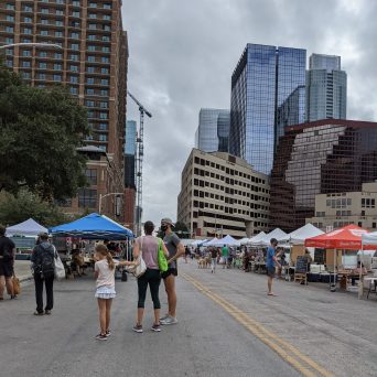 a group of people walking around at SFC farmers market downtown Austin