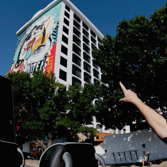 A woman pointing at a mural on the side of a building.