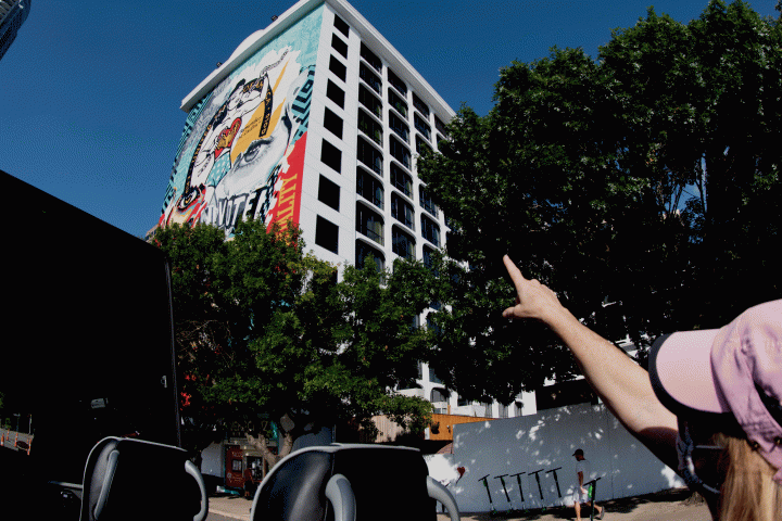 A woman pointing at a mural on the side of a building.
