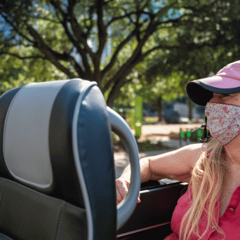 Blond woman with pink hat and floral mask on tour