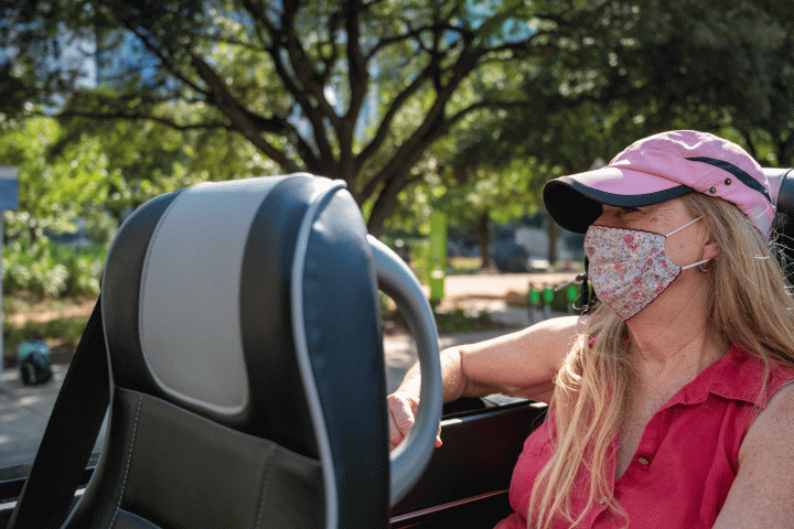 Blond woman with pink hat and floral mask on tour