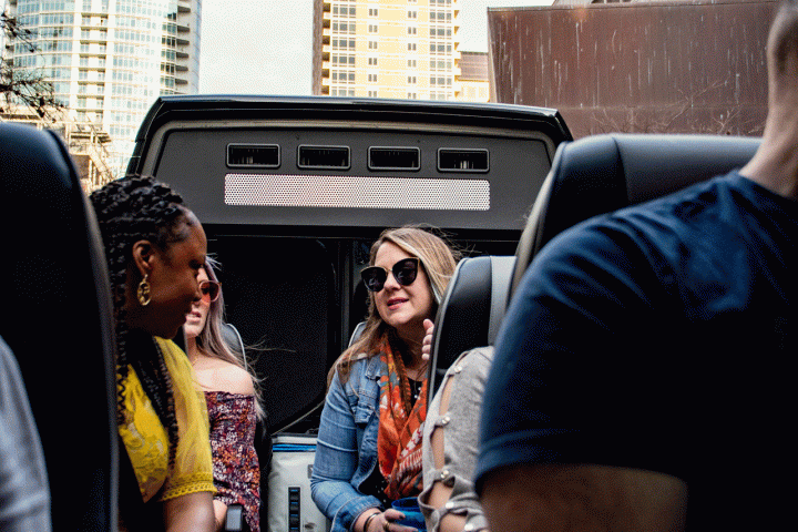 a group of people sitting in the AO Tours Austin Panoramic Bus as it passes under buildings
