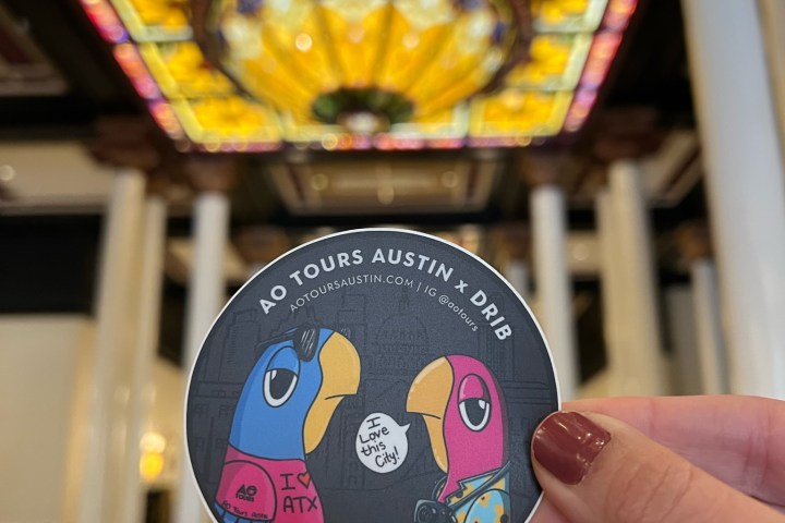 Drib x AO Tours Austin Sticker being held up insde the entrance of the driskill hotel